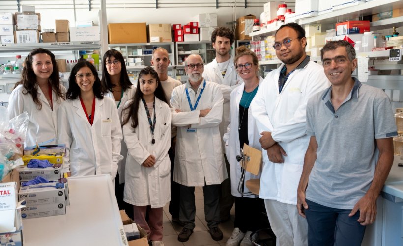 A group of ten people standing in a medical laboratory for a team photo