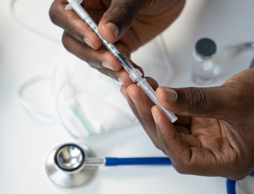 Closeup photo of two hands holding a small syringe with an insulin injection...