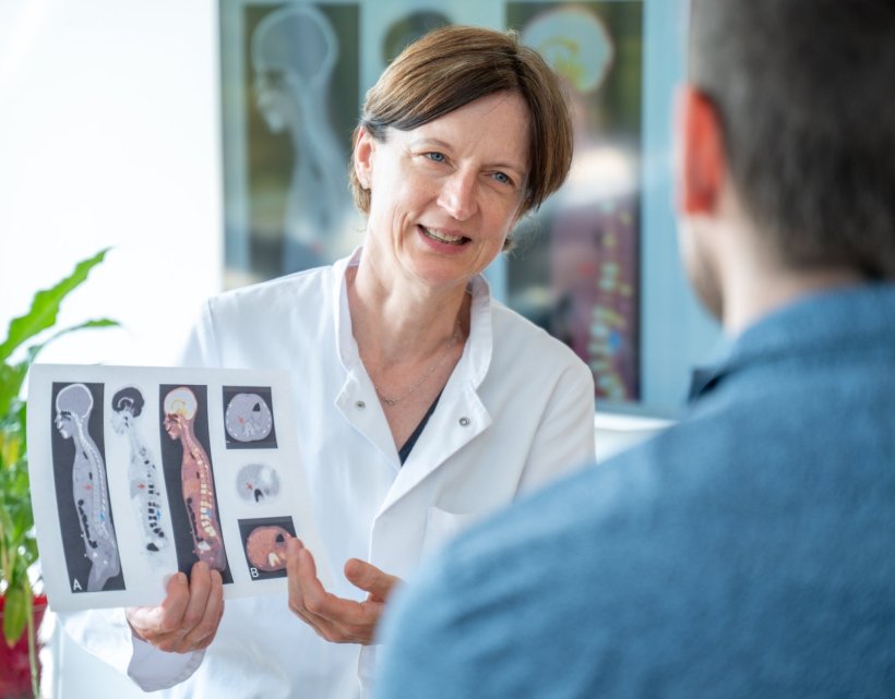 Prof. Simone Hettmer sitzt einem Patienten gegenüber. Sie hält ein Blatt...