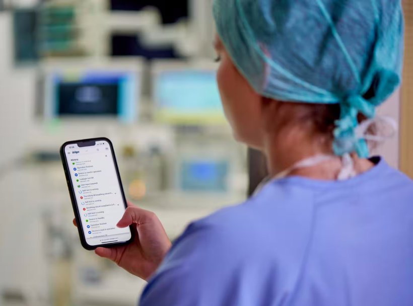 Blick über die Schulter einer Anästhesistin, die auf ein Smartphone schaut