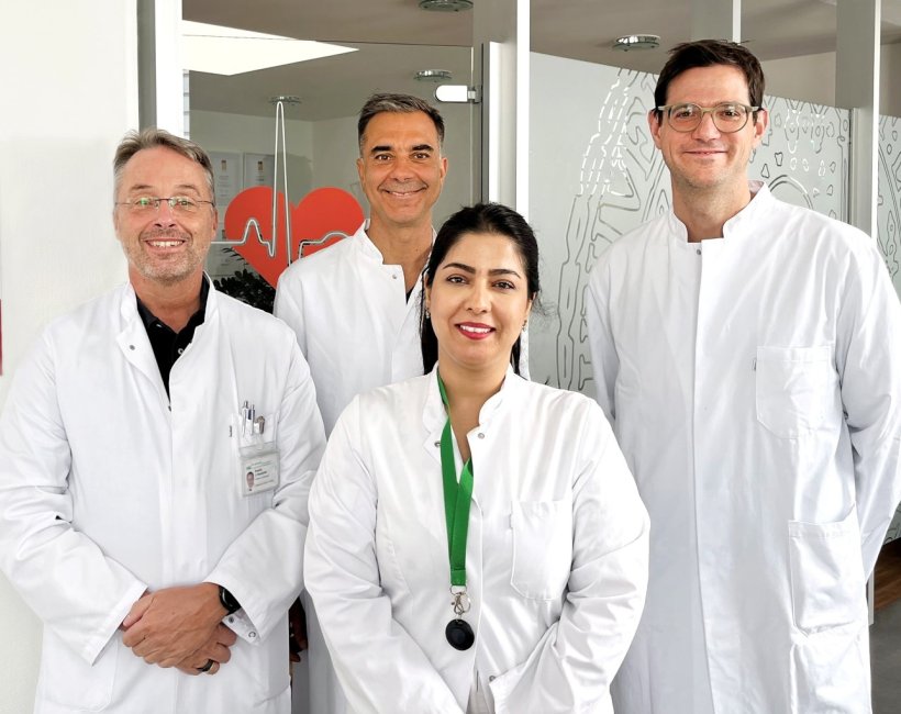 Vier Personen stehen für ein Teamfoto im hellen Flur eines Herzzentrums