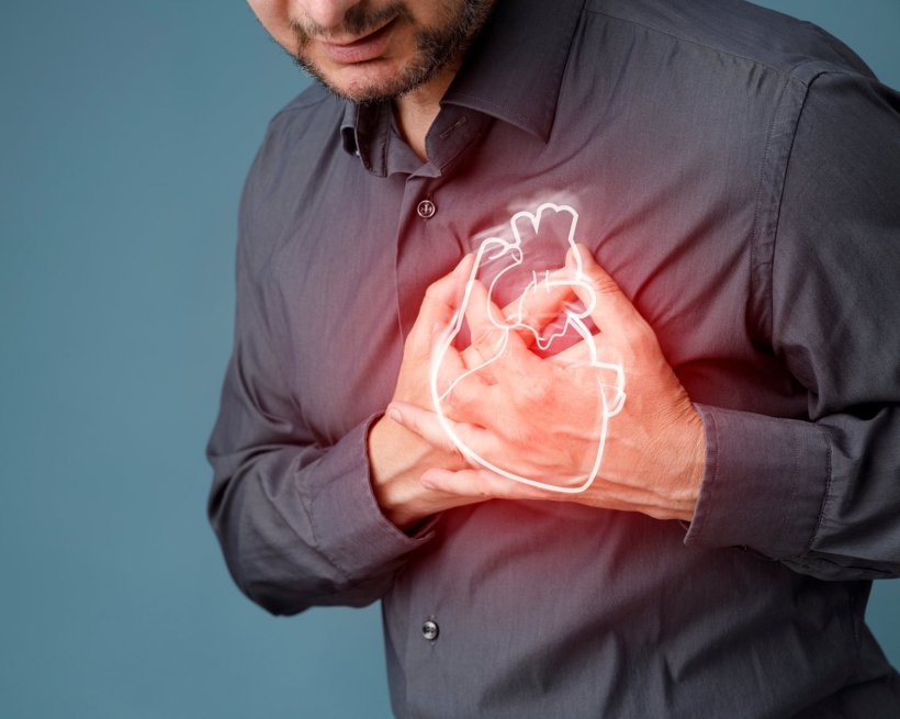 A man is clutching his chest while having a heart attack. The heart is...