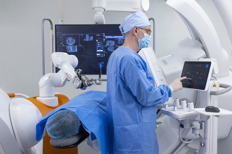 A surgeon is operating a touchscreen in an operating theater. Next to him, a...