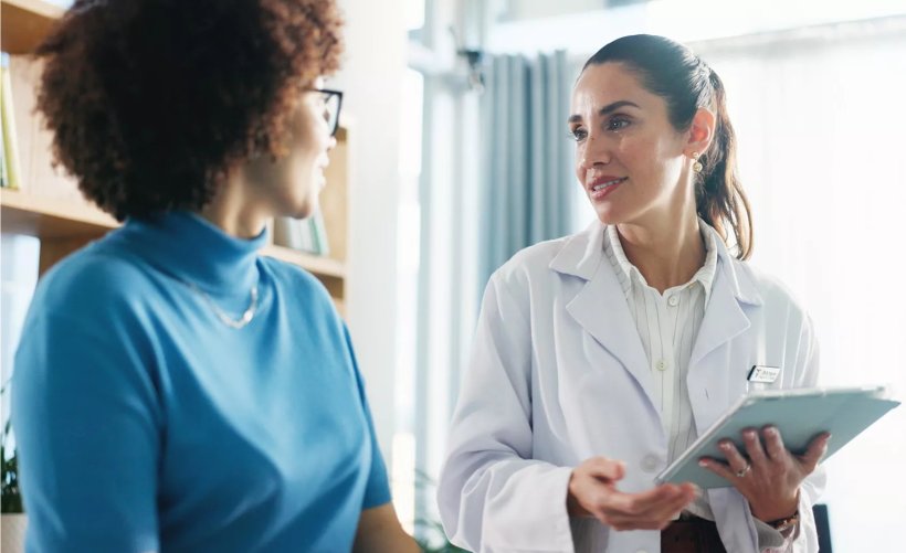 Eine Ärztin im Gespräch mit ihrer Patientin. Die Ärztin hält ein Tablet in...