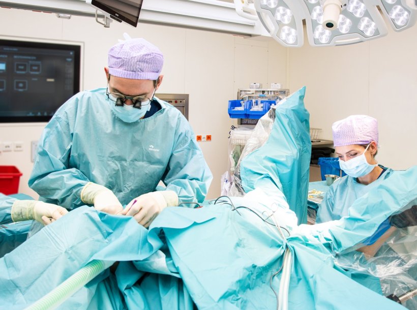Two surgeopns performing surgery on a patient in a hospitals operating room