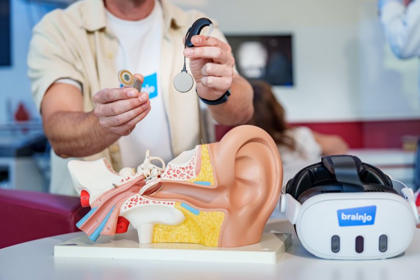 Ein Mann hält die Komponenten eines Cochlea-Implantats in die Kamera, sein...