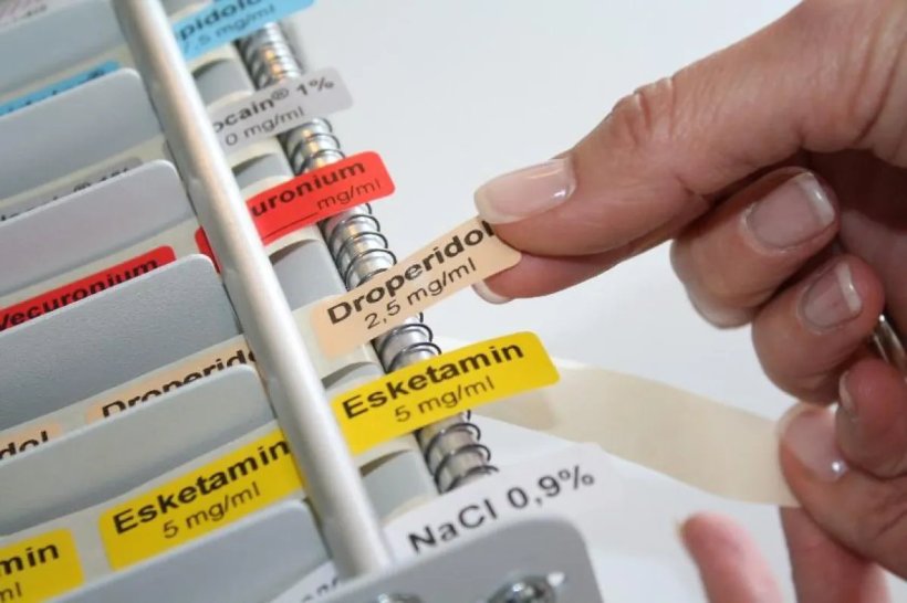 Nahaufnahme einer Hand, die medizinsiche Etiketten hält
