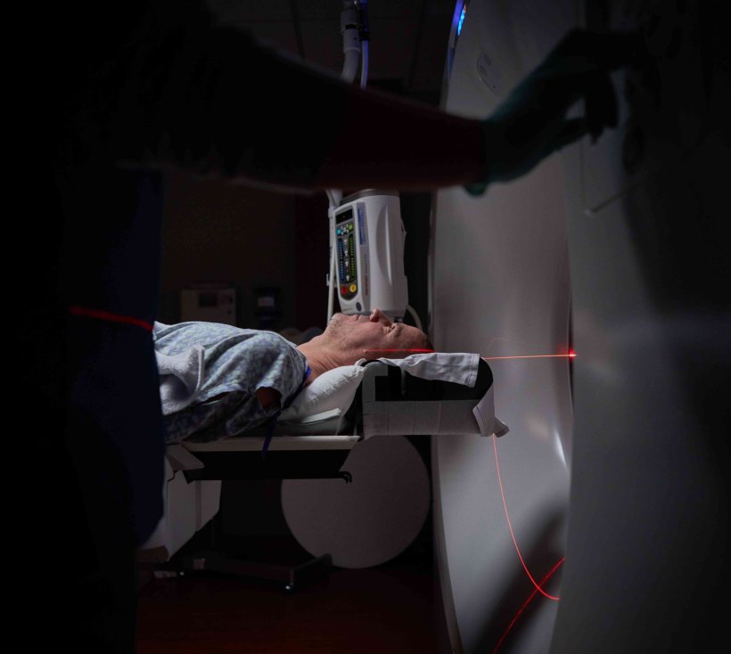 A patient is undergoing radiation therapy in a hospital. He is positioned to...