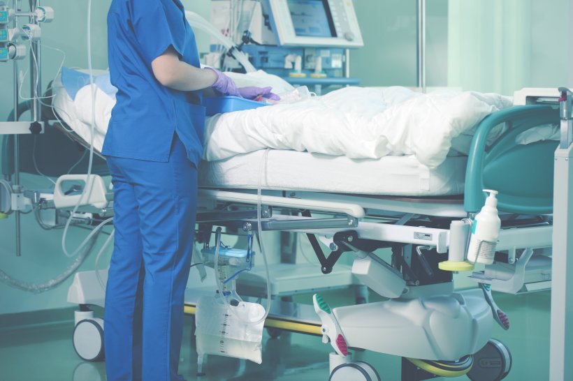 A medical nurse is caring for a patient in a hospital bed in the ICU