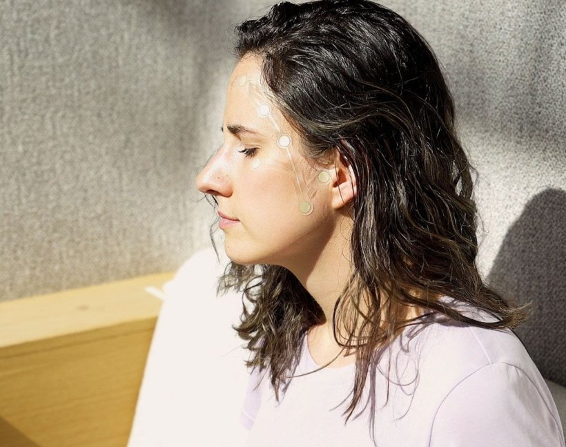 Eine Frau mit geschlossenen Augen im Profil. An ihrer Stirn sind transparente...