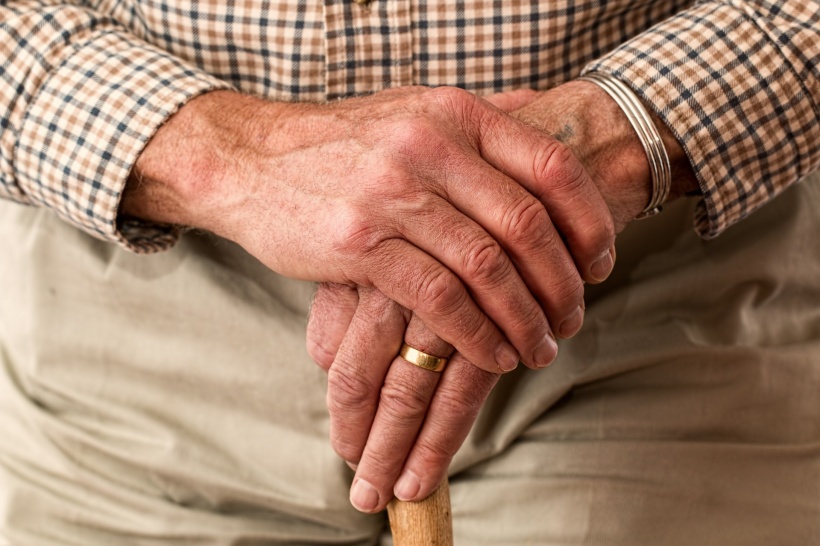 hands of an older person holding a cane