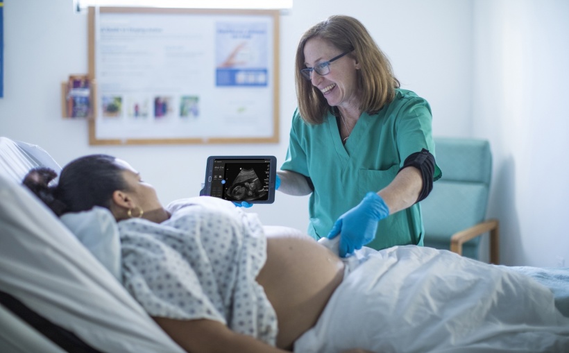 gynecologist showing pregnant patient ultrasound image on mobile device