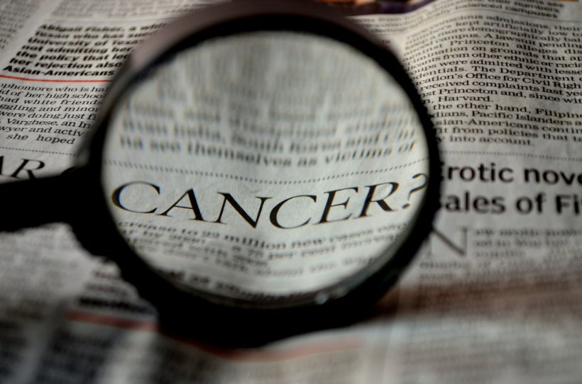 magnifying glass highlighting the word cancer? on a newspaper