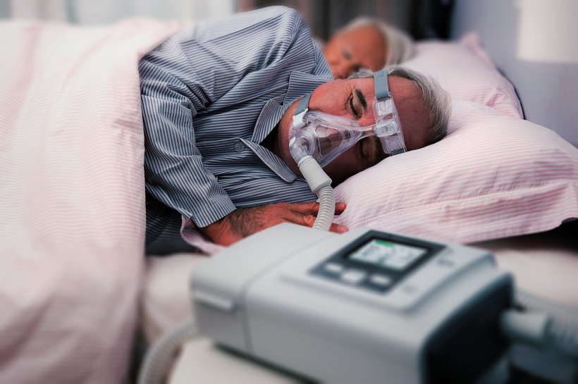 older man with copd breathing mask and ventilation apparatus lying in bed