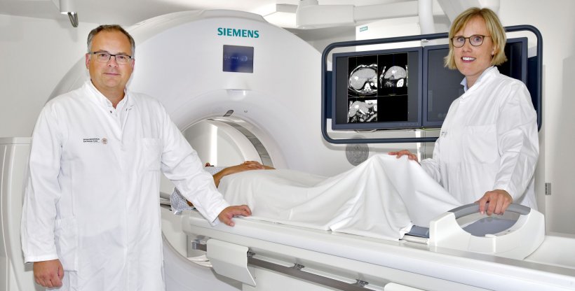 two radiologists standing in front of a computer tomograph