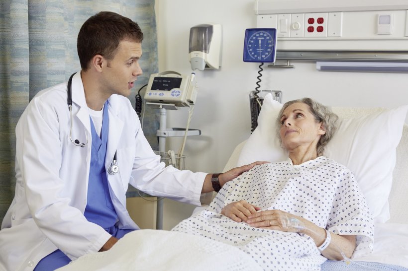 doctor sitting at a patient bed next to female patient