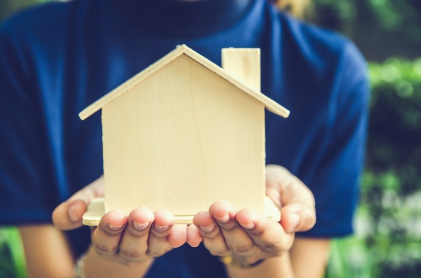 hands holding a small model house