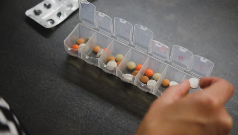 person taking medication from medicine organizer