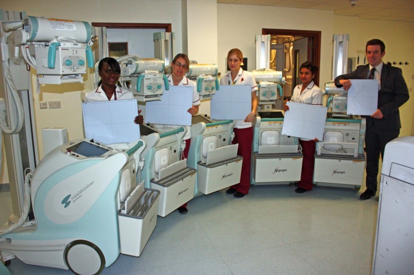 Photo of a group standing in a semicircle behind mobile x-ray systems