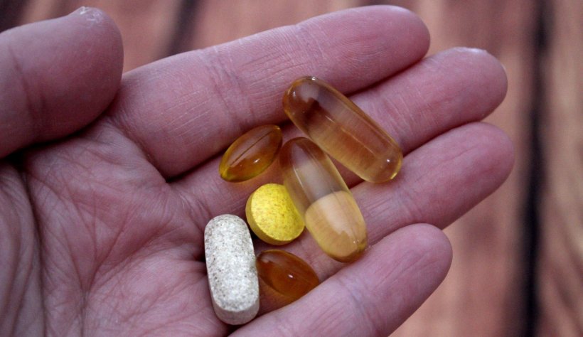 closeup photo of hand holding several pills and tablets