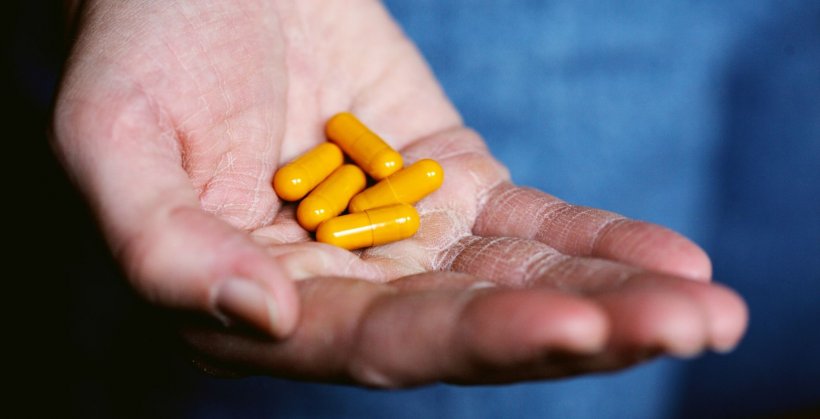 closeup of hand holding orange pills