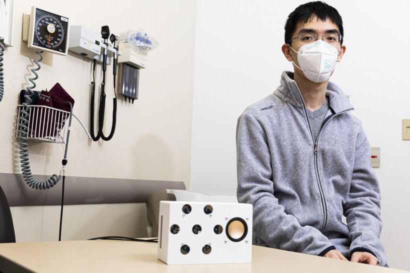 Lead author Anran Wang sits with the smart speaker prototype (white box in...