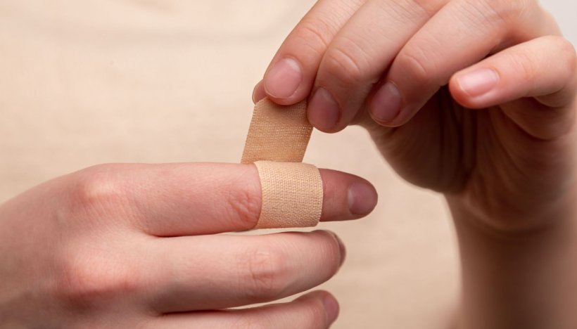 person applying adhesive plaster to their index finger