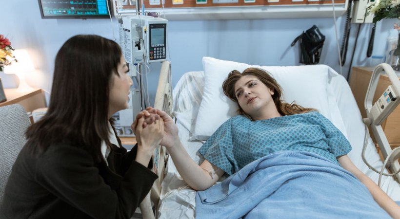 woman in black visiting patient in hospital bed