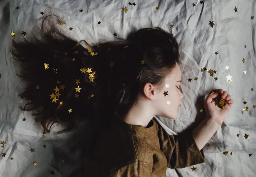 young girl sleeping among star-shaped glitter