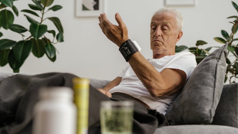 older man checking blood pressure with monitoring gadget on wrist