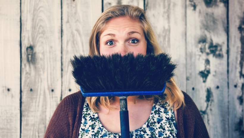 woman holding broom in front of her face