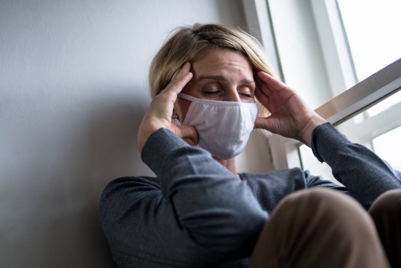Woman wearing face mask at home feeling stressed during coronavirus pandemic
