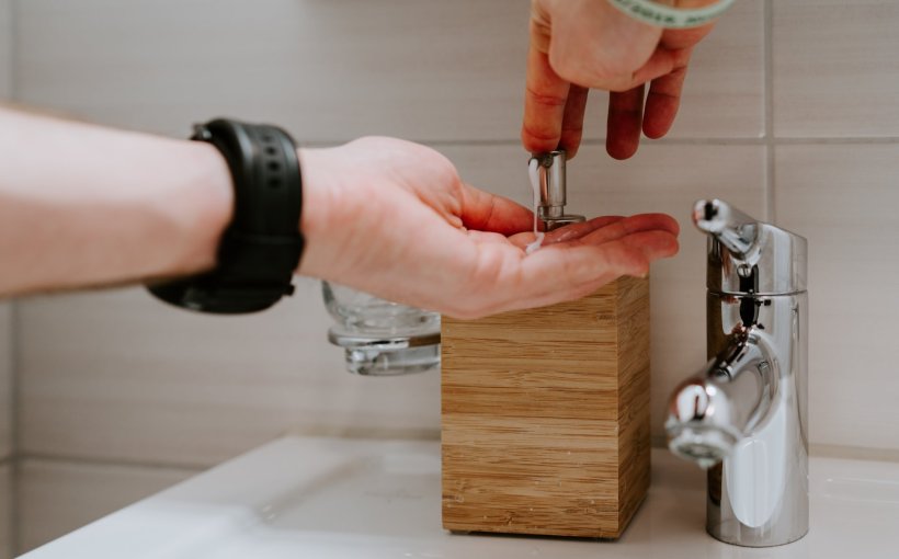 person using liquid soap dispenser at bathroom sink