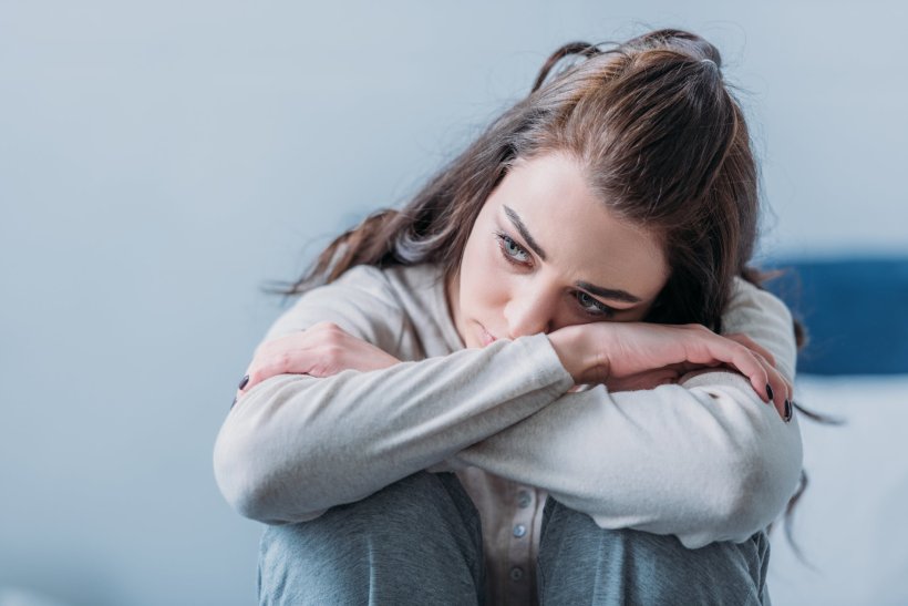 selective focus of beautiful sad woman hugging knees and looking away