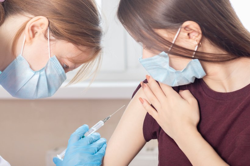 female doctor giving vaccine shot to teenage girl