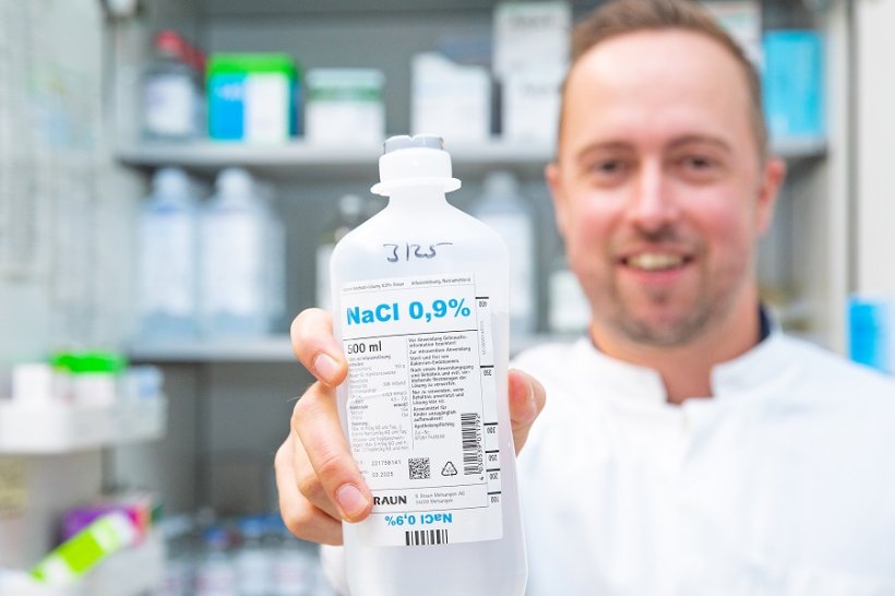 Professor Dr. Nico Lachmann mit einer Flasche Natriumchlorid-Infusionslösung....