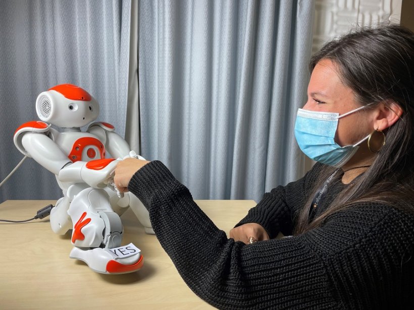 Nao robot shaking hands with study co-author Dr Micol Spitale.