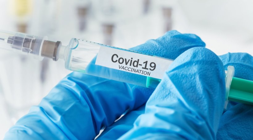 coronavirus vaccine syringe in blue gloved hand