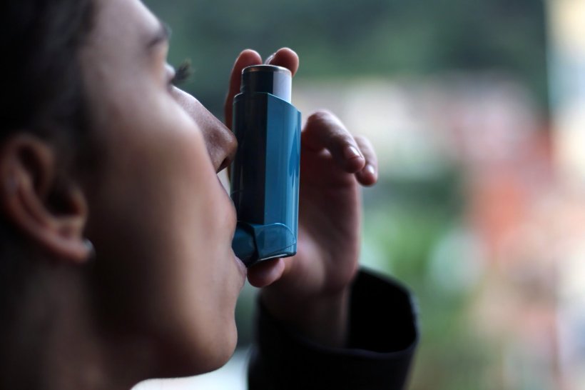 young woman using inhaler for her asthma medication