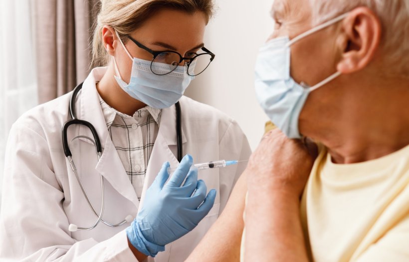 doctor giving vaccine injection to elderly male patient