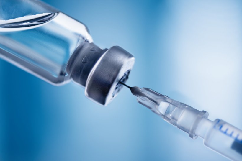 Glass vial and syringe with injection over blue background