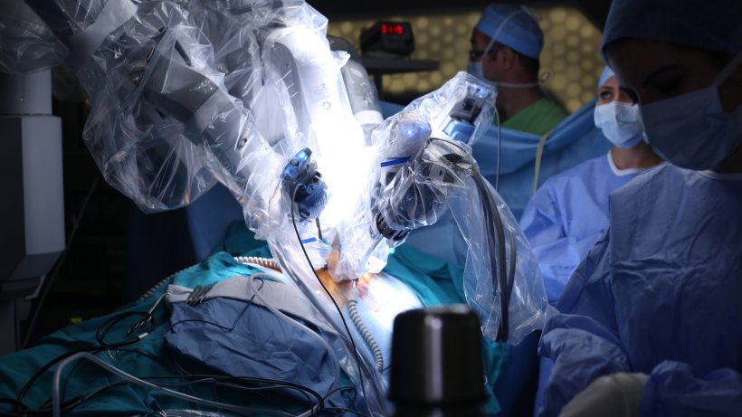 surgical robotic system in OR performing surgery under observation of surgeons