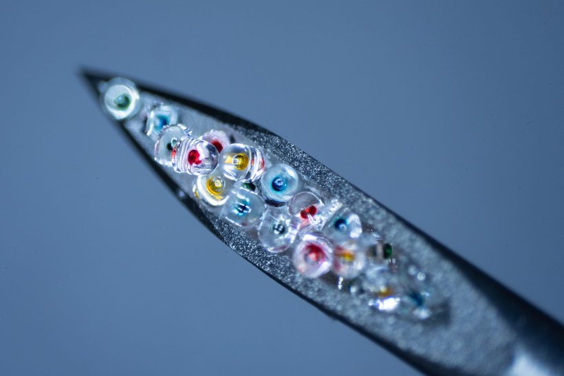 Sealed microparticles containing colored dye are shown inside the narrow...