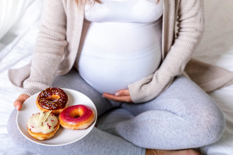 pregnant woman holding plate with three colorful donuts, unhealthy eating, food