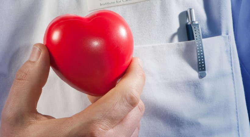 closeup photo of man in white doctors coat holding red heart-shaped object