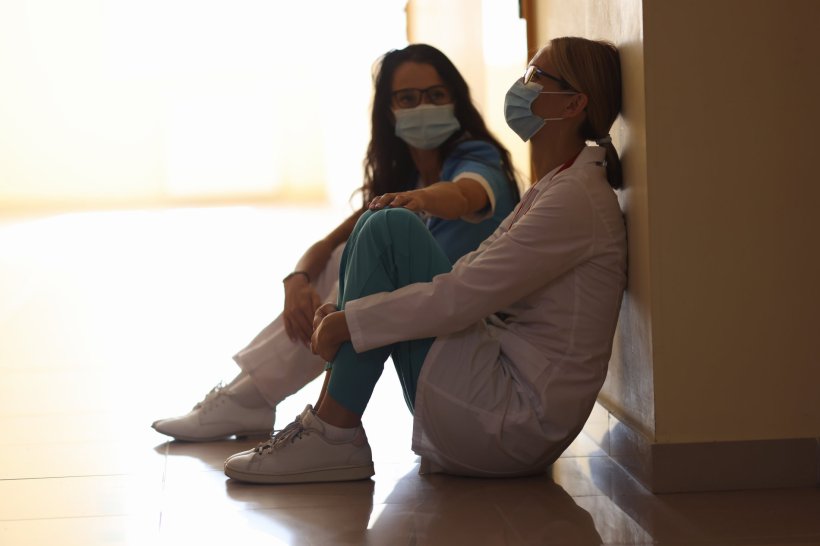 tired medical personnel sitting in a hospital hallway