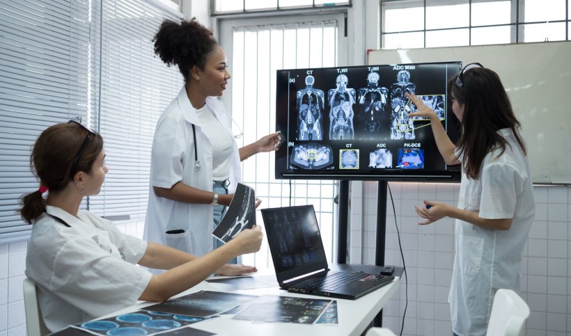 group of three female medical professionals discussing xray radiology images