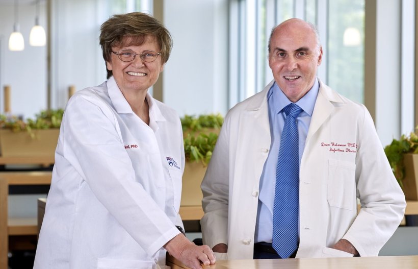 Katalin Karikó and Drew Weissman standing behind wooden table