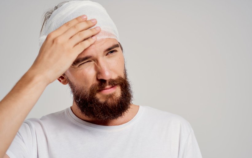 bearded man with bandage around his head after concussion or accident
