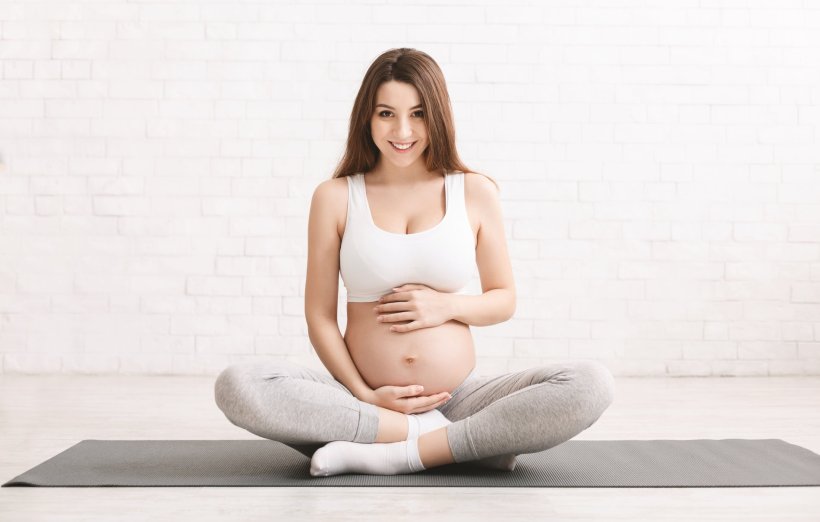 pregnant woman doing yoga sitting on the floor